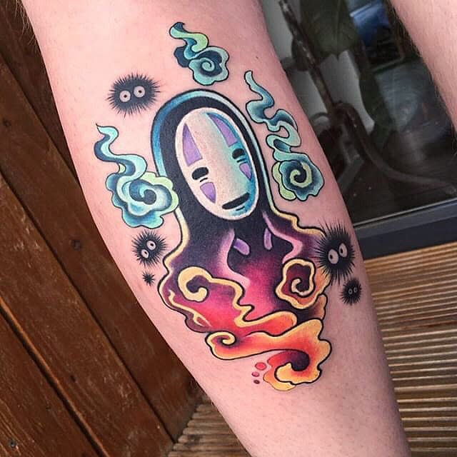 Colorful tattoo of an animated mask character with black and glowing elements